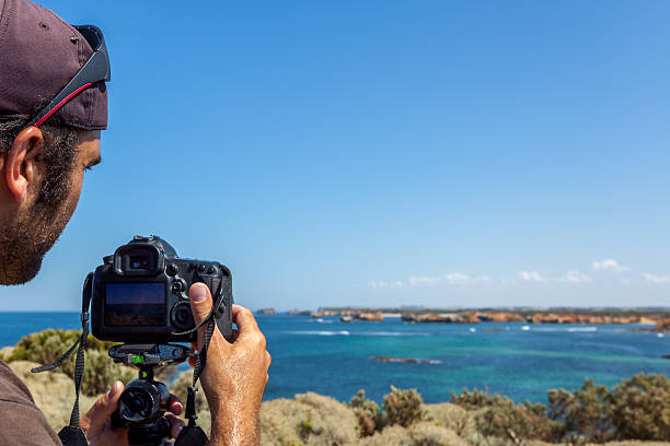 uomo prendendo foto di fotografo con una fotocamera reflex sulla spiaggia - australia photographing camera beach foto e immagini stock