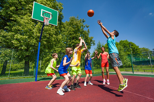 Two friends playing basketball. Both about 12 years old, African and Caucasian females.