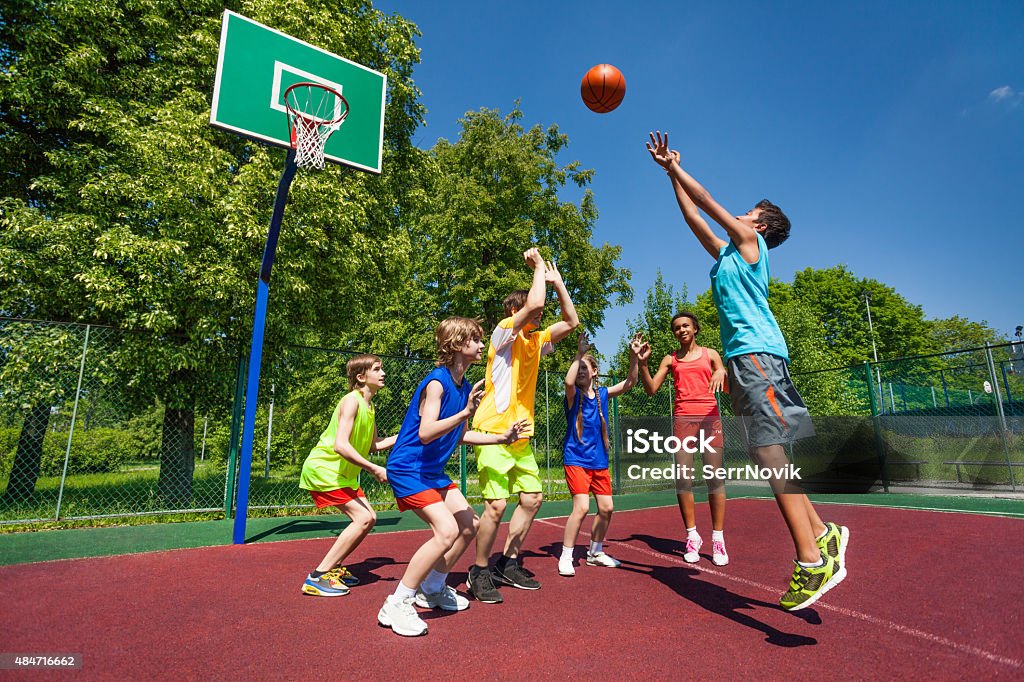 Teenagers playing basketball game together Teenagers playing basketball game together on the playground during sunny summer day Basketball - Sport Stock Photo