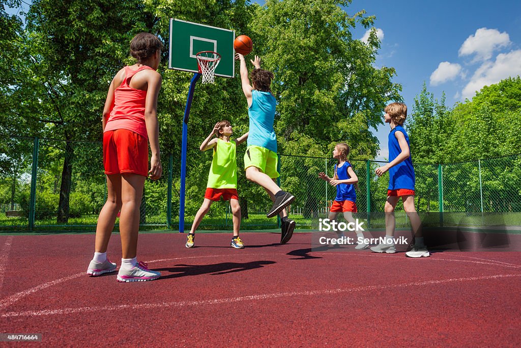 Equipo de colorido uniformes jugar juego de básquetbol - Foto de stock de Baloncesto libre de derechos