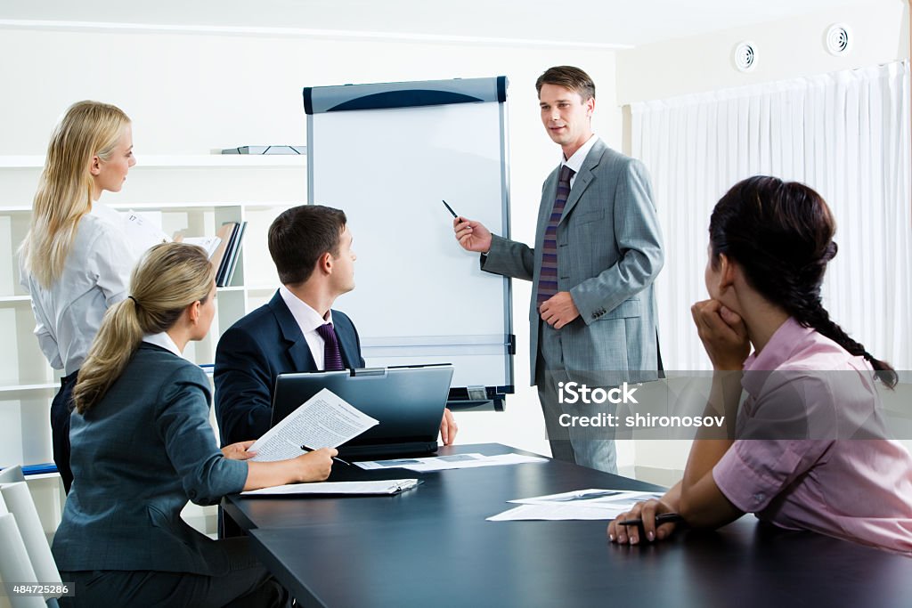 Seminar Image of smart business people looking at their leader while he explaining something on whiteboard during seminar 2015 Stock Photo