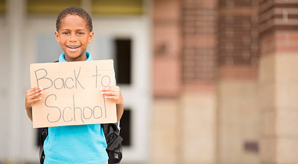 istock African descent, little boy holds back to school sign. 484728456