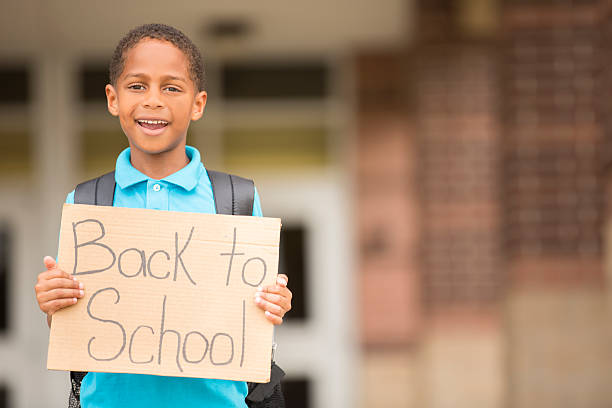 istock African descent, little boy holds back to school sign. 484731700