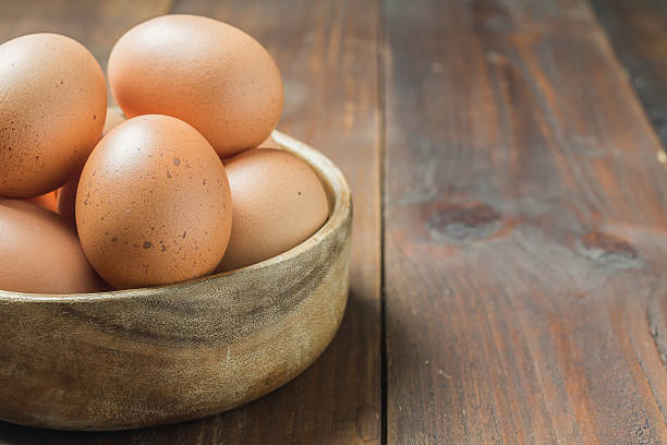 istock Fresh eggs in wood bowl on wood background 484735020
