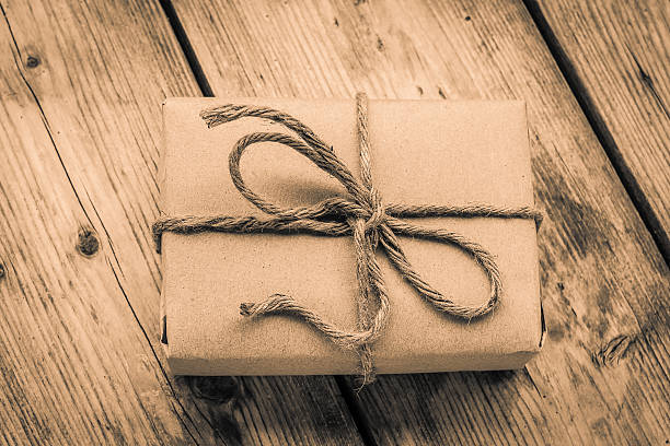 Vintage gift box brown paper wrapped with rope on wood background , antique tone