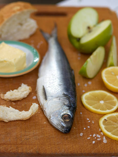 istock Herrings on wooden background with lemon, apple, salt 484739745