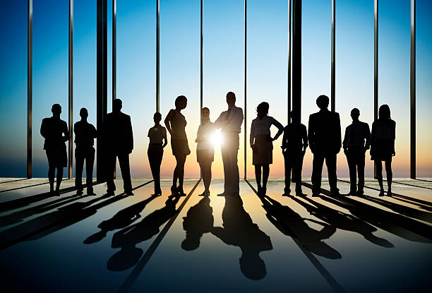 Confident Silhouette Of Business People Posing For The Camera In Confident silhouette of business people posing for the camera indoors. business people silhouette stock pictures, royalty-free photos & images
