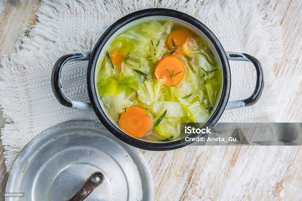 Cabbage soup in a pot Fresh cabbage soup in a pot on white wooden table Soup Stock Photo