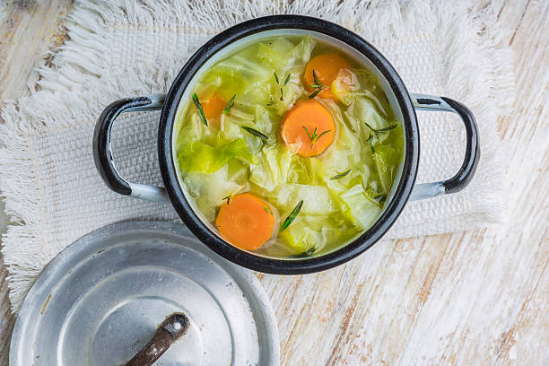 Cabbage soup in a pot Fresh cabbage soup in a pot on white wooden table cabbage stock pictures, royalty-free photos & images