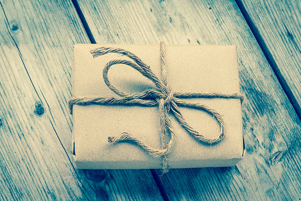 Vintage gift box brown paper wrapped with rope on wood background , vintage tone