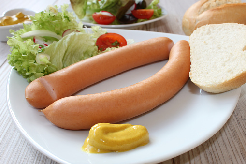 hot dogs with side salad, bread and mustard
