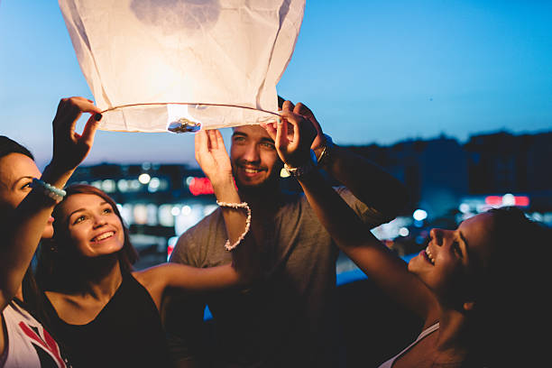 amigos na cobertura, liberando luminária de papel no céu - lantern wishing sky night - fotografias e filmes do acervo