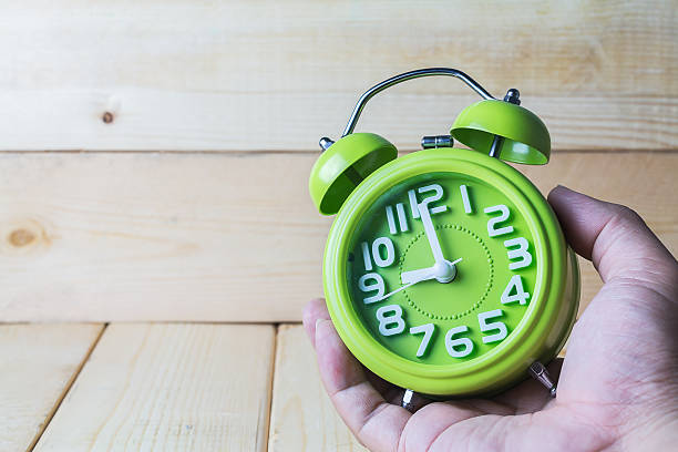 istock Hand hold Green alarm clock on wood background 484744660