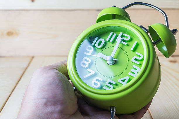 istock Hand hold Green alarm clock on wood background 484744676