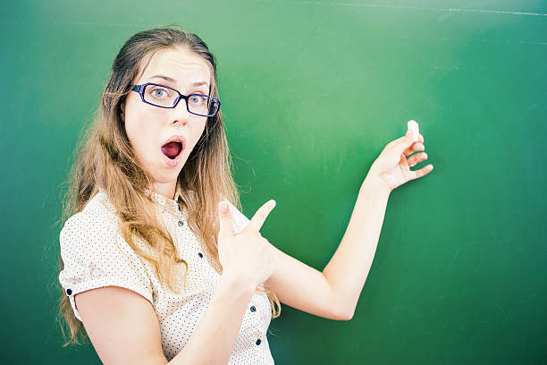 istock Happy young teacher or student is pointing at blackboard background 484752648