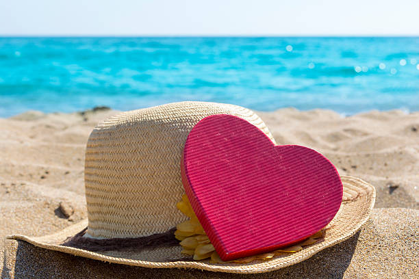 istock Straw hat and a heart shape on the sandy beach 484754222
