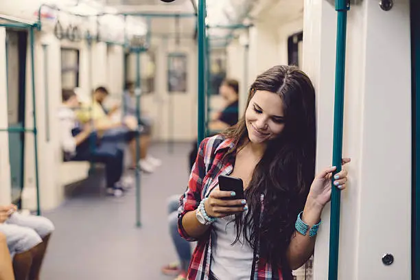 Photo of Teenage girl using phone while travelling in the subway train