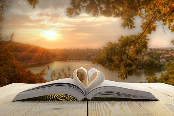 Open book on wooden table on natural blurred background.