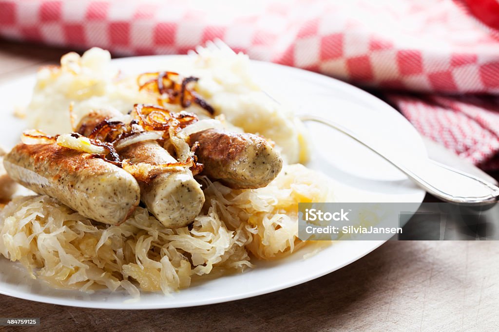 sauerkraut and tofu sausages Sauerkraut and sausages, made from Tofu, on a white plate, decorated with rings of fried onions, mashed potatos in the background, vegetarian version of a classical german recipe Sauerkraut Stock Photo