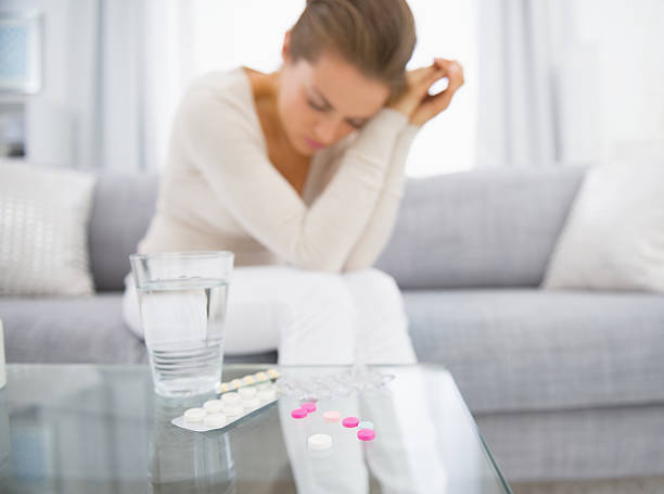Pills on table and young woman in background. Closeup