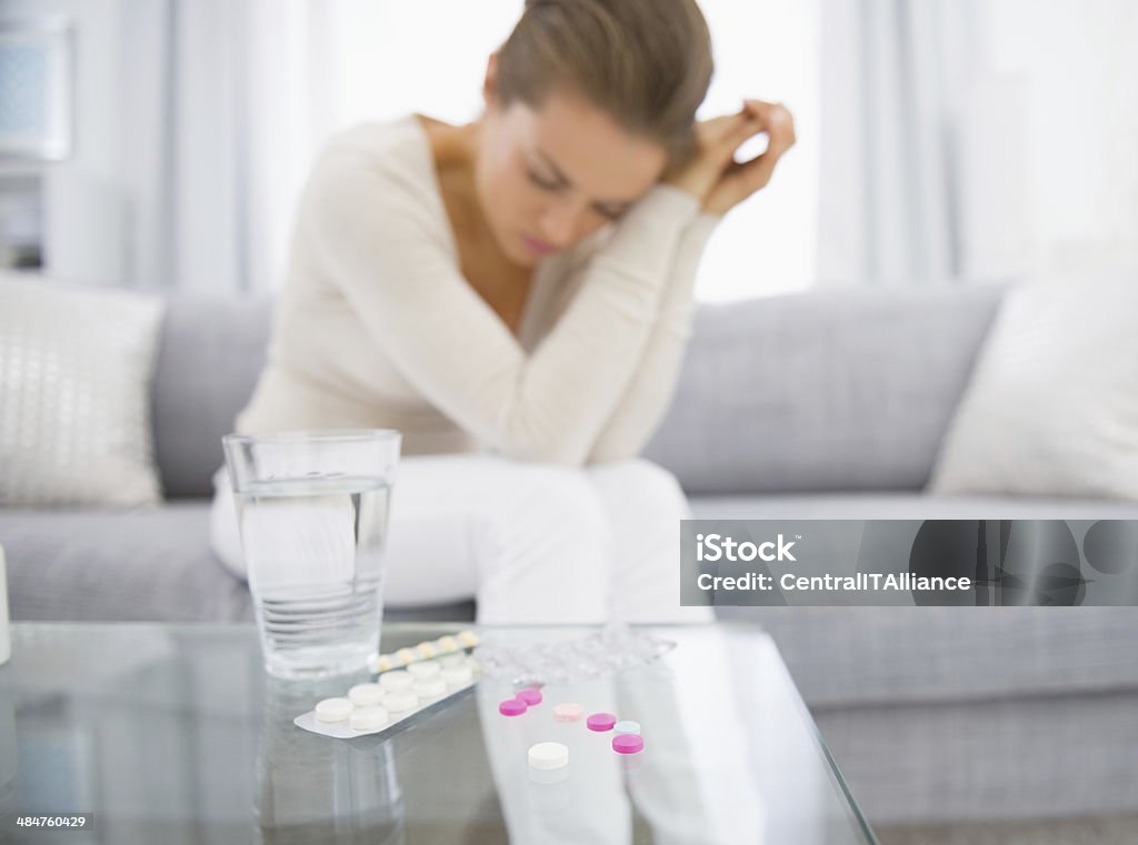 Pills on table and young woman in background. Closeup Closeup on pills on table and young woman in background Adult Stock Photo