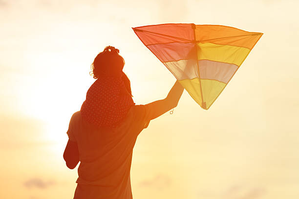 istock father and little daughter flying kite at sunset 484762942