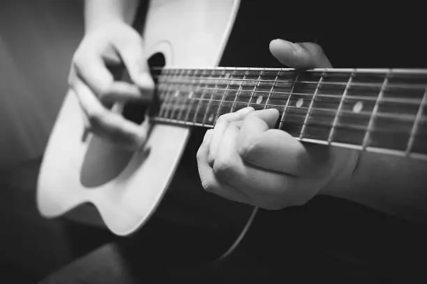 Photo of Close up hands playing acoustic guitar