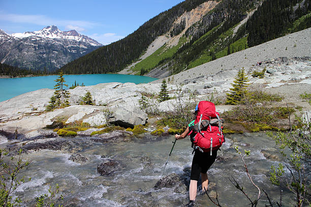 istock Woman hiker walking across a clear mountain stream 484771540
