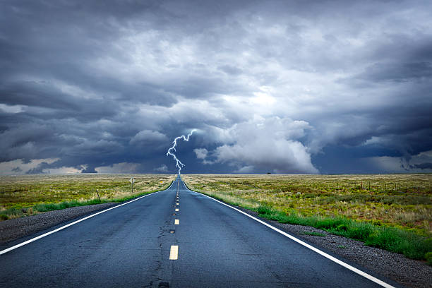 Lightning Bolt At The End Of Long Rural Road A stormy sky with  lightning bolt at the end of a long rural road. Room for text. vanishing point stock pictures, royalty-free photos & images