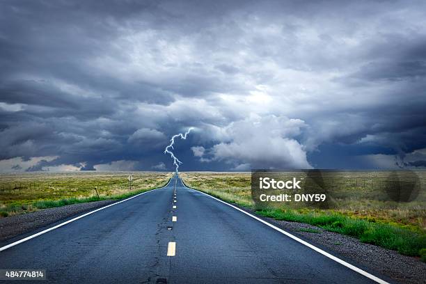Lightning Bolt At The End Of Long Rural Road Stock Photo - Download Image Now - Lightning, Vanishing Point, Storm