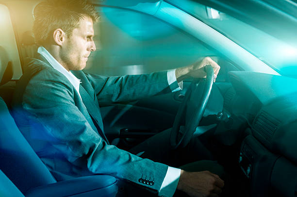 istock Man wears suit and drives car at night 484776224