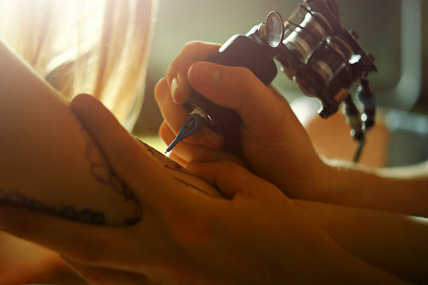 istock Tattoo master tattooing on the a girl arm. 484778570
