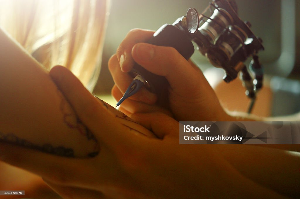 Tattoo master tattooing on the a girl arm. 20-24 Years Stock Photo