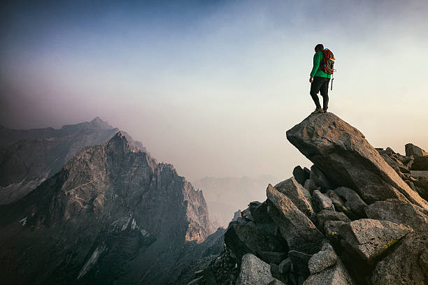 Mountain climbing Strong mountain climber looking into distance during a sunset as clouds roll in  view from mountain top stock pictures, royalty-free photos & images