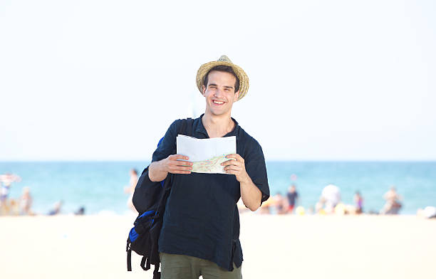 istock Smiling travel man standing by the beach with map 484786202