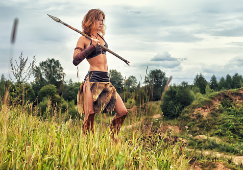 Beautiful red-haired girl in the image of ancient warriors on the background of nature.