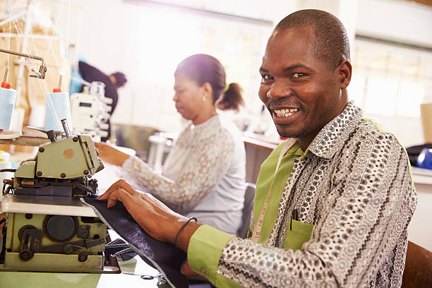 sorridente homem costura em uma comunidade workshop, a áfrica do sul - south africa waist up indoors image technique imagens e fotografias de stock
