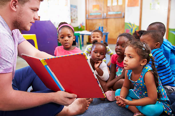 voluntarios profesor de lectura a una clase de preescolar niños - africa african descent education child fotografías e imágenes de stock