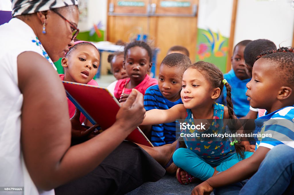 Teacher reading a book with a class of preschool children Child Stock Photo