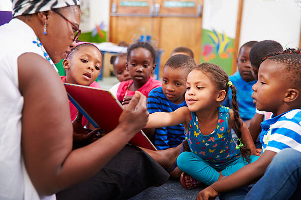 teacher reading a book with a class of preschool children - afrikanskt ursprung bildbanksfoton och bilder