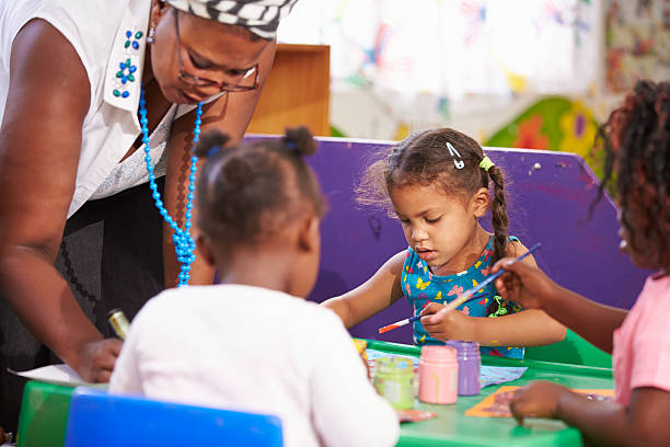 istock Teacher helping kids in a preschool class, close up 484794666