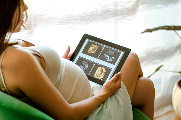 Pregnant woman watching baby ultrasound scan on a tablet pc stock photo