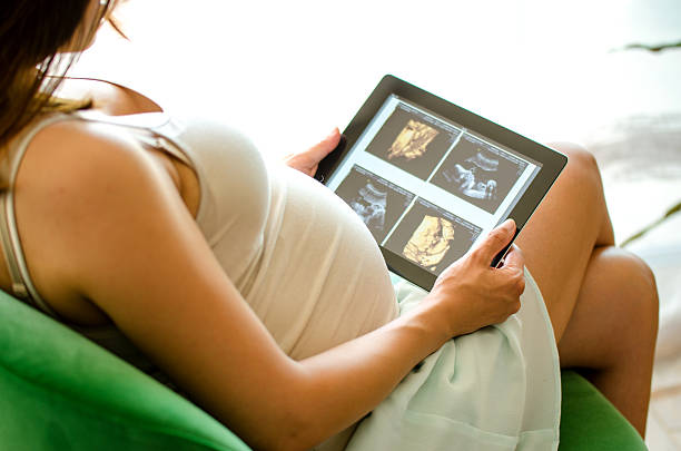 Pregnant woman watching baby ultrasound scan on a tablet pc stock photo