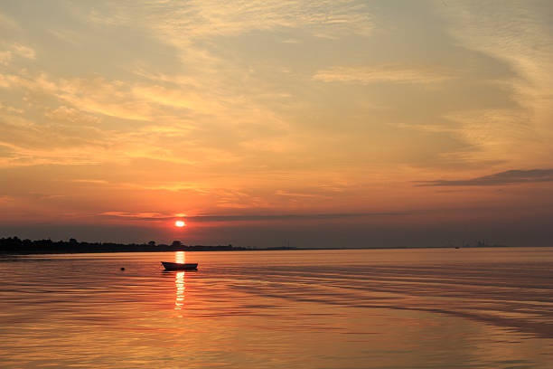 istock Boat in the ocean with the sun rising behind it 484797456