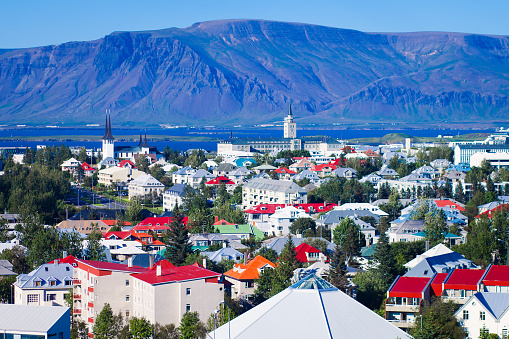 Beautiful summer super wide-angle aerial view of Reykjavik, Iceland with harbor and skyline mountains and scenery beyond the city, seen from the observation tower of hallgrimskirkja church with blue sky in sunny day.