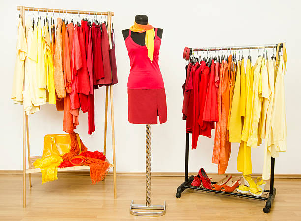 istock Wardrobe with yellow, orange and red clothes arranged on hangers. 484800584