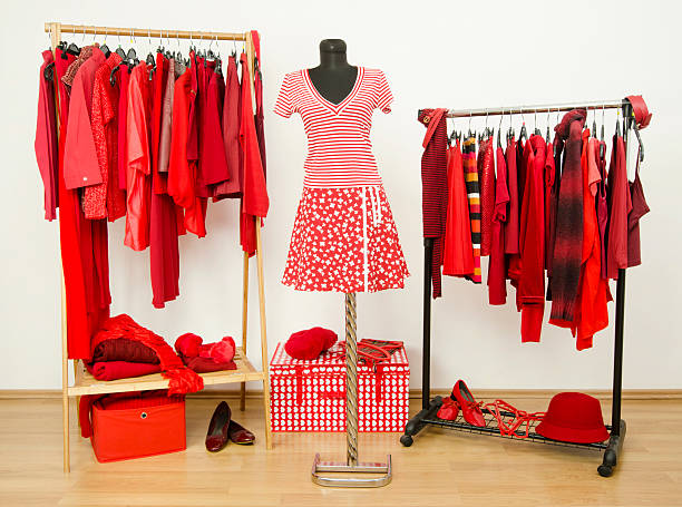 istock Dressing closet with red clothes arranged on hangers. 484800586