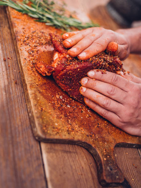 istock Raw pork being seasoned by hand on a wooden board 484806888