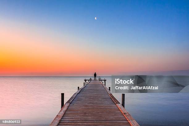 Mann Stehend Auf Anlegesteg Am Strand Mit Sunrise Und Mond Stockfoto und mehr Bilder von Ende