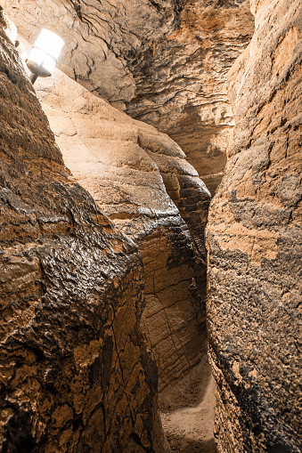 Vertical photography composition of majestic natural rock eroded by water and time, maze narrow passage footpath in french Caves of La Balme, with abstract rock formation. Famous smuggler eighteenth century (XVIIIeme), legend says Mandrin, 